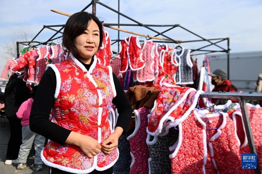 12月29日，在山東青島西海岸新區(qū)泊里大集，一名消費(fèi)者在試穿新年喜慶服裝。

2025新年將至，各地布置一新，舉行多彩活動(dòng)，在紅紅火火中迎接新年。

新華社發(fā)（俞方平攝）