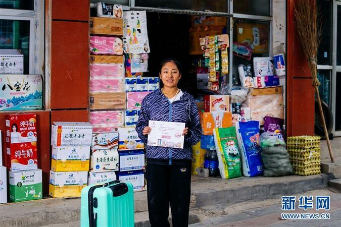 9月16日，在青海省化隆回族自治縣巴燕鎮(zhèn)，娘毛吉在鄉(xiāng)間班車停靠點(diǎn)邊的小賣部前展示自己的大學(xué)錄取通知書。新華社記者 劉金海 攝