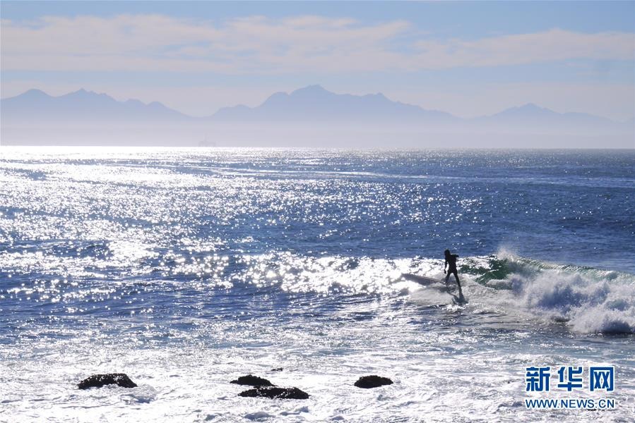 2019年5月2日，沖浪者在南非莫塞爾灣的海濱乘浪前行。新華社發(fā)（孫茵攝）