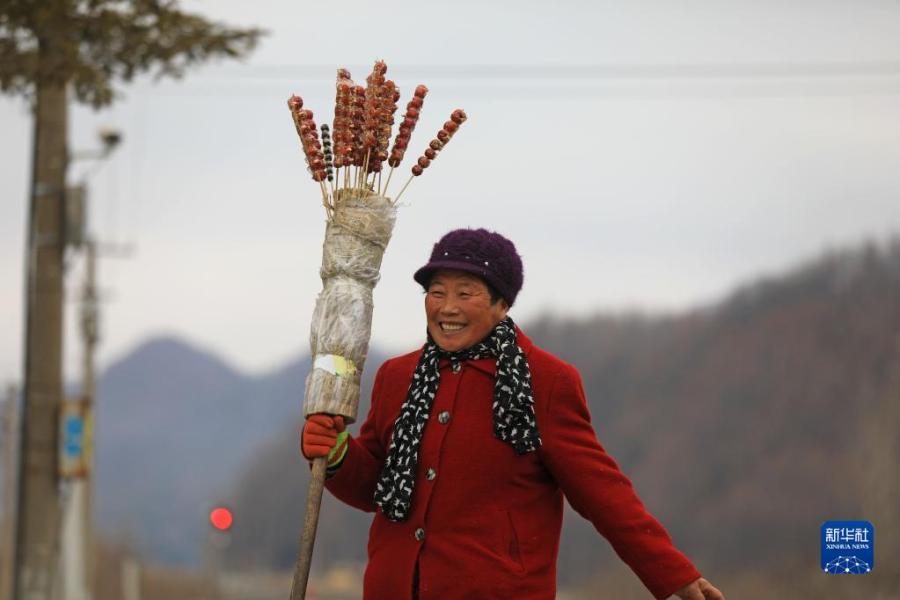 1月15日，在辽宁省凤城市石城站，一位农民带着自制的糖葫芦准备上车。