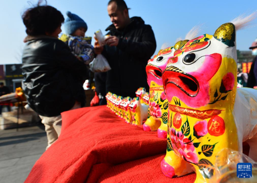 1月11日，在山东省青岛市崂山区沙子口腊月年集上，市民在选购传统泥塑玩具“叫叫虎”。  新华社发（王海滨摄）