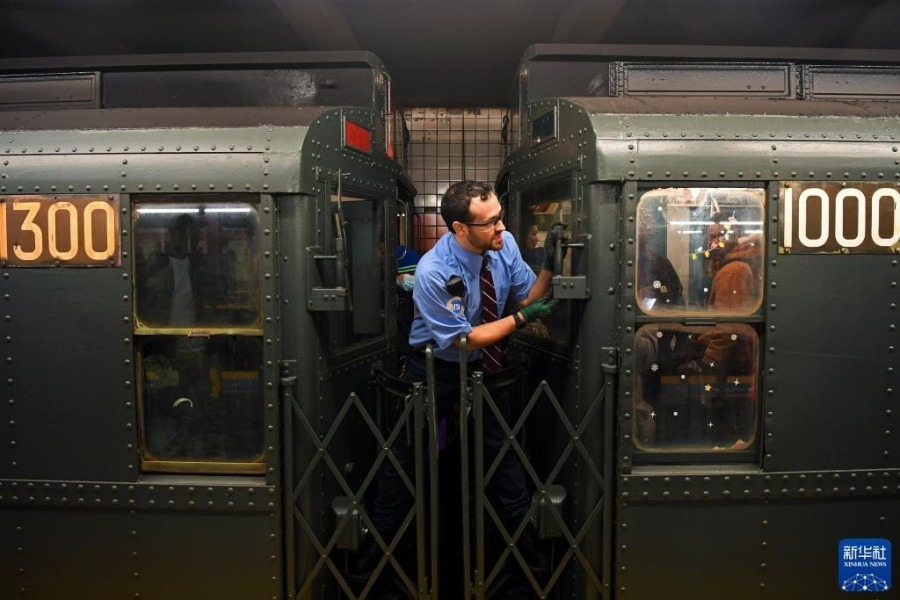 12月2日，在美国纽约，一名工作人员在“怀旧地铁”专列到站后招呼乘客上车。新华社记者 李睿 摄
