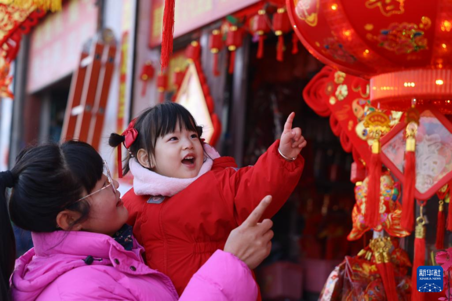 1月11日，在山东省滕州市级索镇，一名小朋友被年集上销售的红灯笼吸引。 新华社发（钟家增摄）