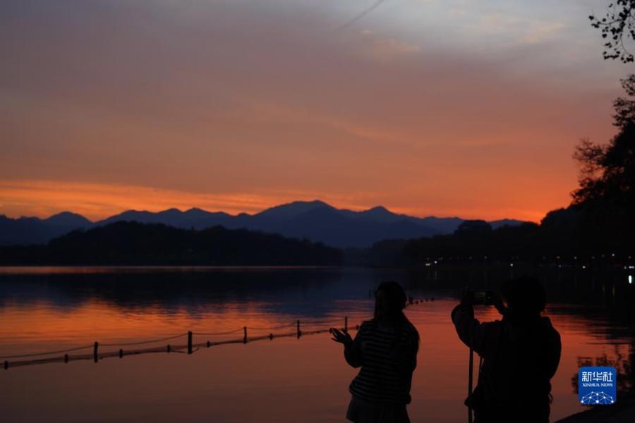12月5日，游客在杭州西湖拍摄晚霞。

新华社发（庄颖昶摄）