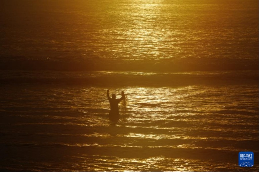 1月18日，在瑙鲁国际机场附近的海边，一名男子使用渔网捕获海产品。新华社记者 王申 摄