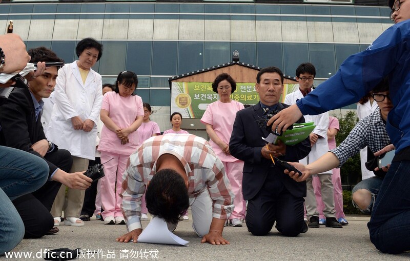 图说：当地时间2014年5月28日，据韩国媒体报道，韩国南部长城郡地区的一家疗养院发生火灾，导致21人死亡。死者多为70到80岁卧床不起的老人。图为疗养院的相关负责人跪地道歉。