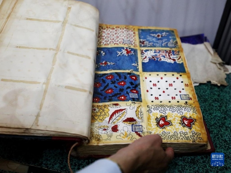 8月11日，在英国麦克尔斯菲尔德一家丝绸工厂，工作人员展示有关丝绸的古代书籍。新华社记者 李颖 摄