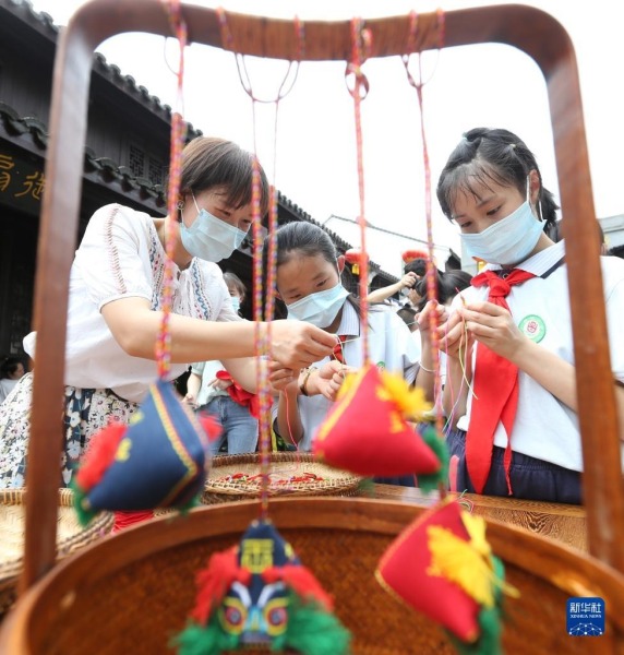 5月30日，在浙江省湖州市安吉县鄣吴镇，学生在老师的指导下制作香囊。新华社发（夏鹏飞 摄）