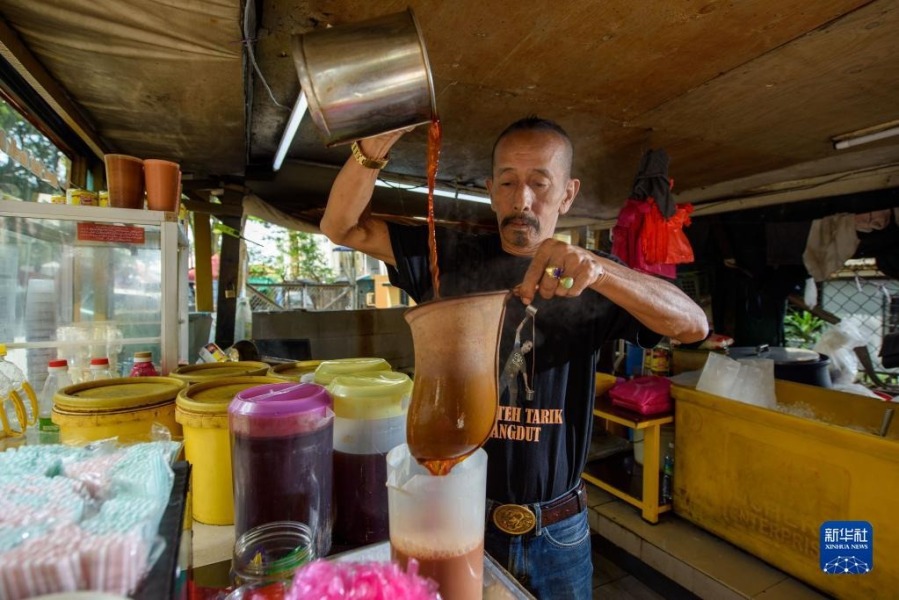 5月18日，在马来西亚雪兰莪州的必打灵查亚，穆赫德·扎布里在制作拉茶。穆赫德·扎布里在必打灵查亚经营拉茶店已超过20年，他制作的拉茶深受当地居民喜爱。新华社发（张纹综摄）