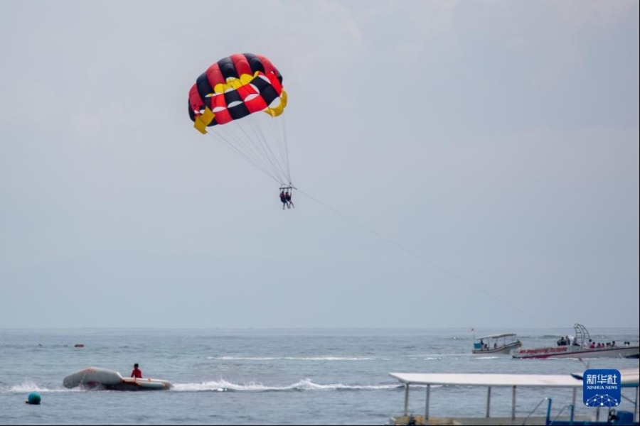 11月12日，在印度尼西亚巴厘岛丹戎伯诺阿海滩，游客体验水上帆伞运动。新华社记者 王益亮 摄