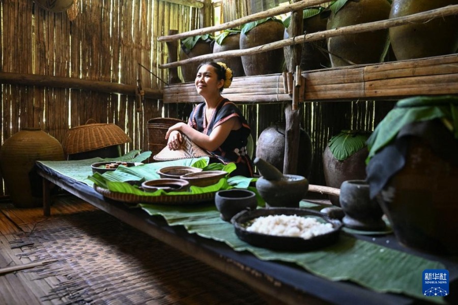 11月14日，在马来西亚沙巴州的马里马里文化村，一名身着传统民族服饰的女子制作糯米酒。新华社记者 程一恒 摄