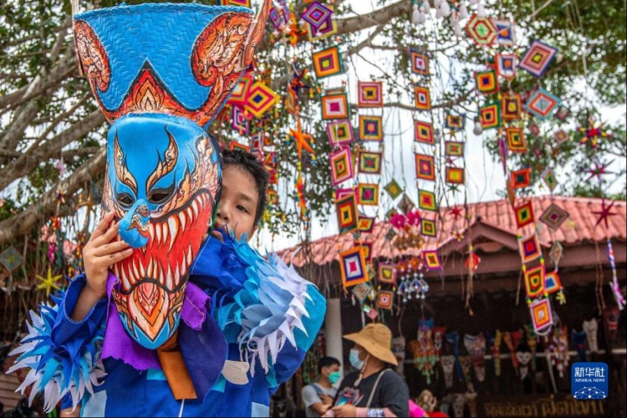 7月1日，在泰国黎府，一名儿童手持面具参加“鬼面节”游行。新华社记者 王腾 摄