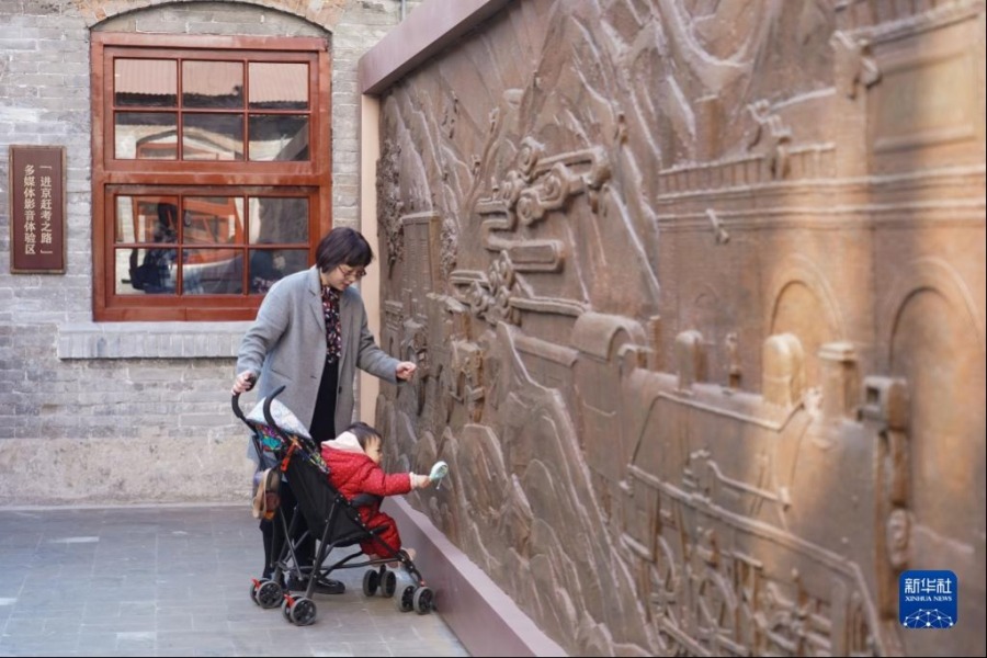3月25日，一位游客带着孩子参观清华园车站旧址内的一处浮雕。新华社记者 陈钟昊 摄