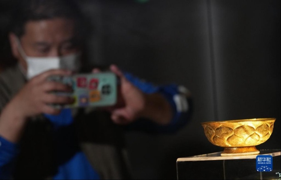 游客在陕西历史博物馆“大唐遗宝——何家村窖藏出土文物展”上拍摄鸳鸯莲瓣纹金碗（2022年5月18日摄）。新华社记者 李一博 摄