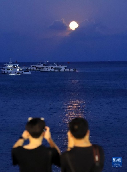 9月10日晚，游客在浙江舟山乌石塘景区观赏“海上生明月”景观。新华社发（邢守秒 摄）