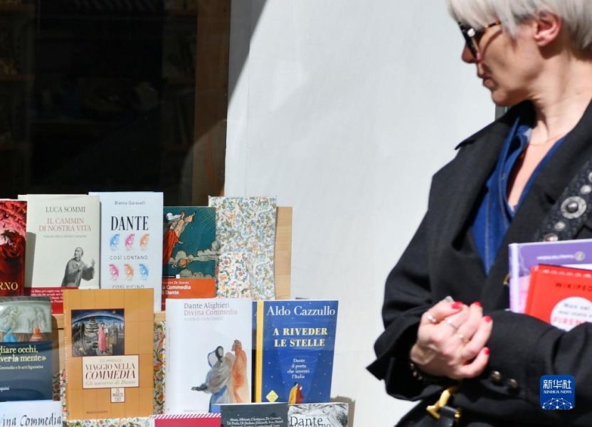 4月14日，在意大利佛罗伦萨，一名女子经过摆放着但丁相关书籍的展示架。新华社记者 金马梦妮 摄