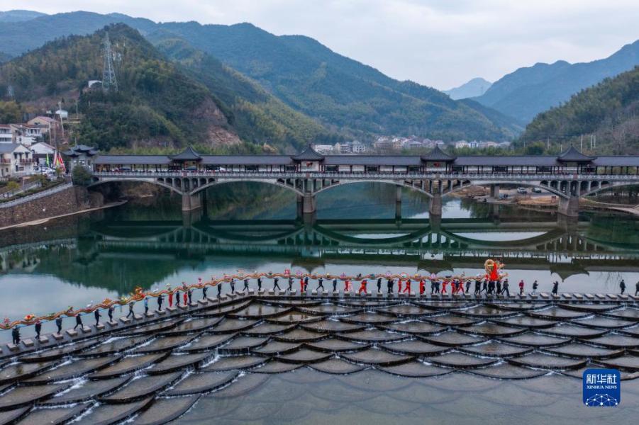 2月1日，窈口村女子板龙队在湖源乡的龙鳞坝碇步桥上进行舞龙表演（无人机照片）。