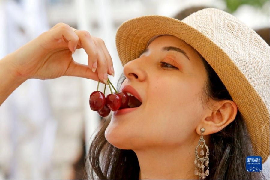 6月11日，一名女子在黎巴嫩哈马纳举办的樱桃节上品尝樱桃。新华社发（比拉尔·贾维希摄）