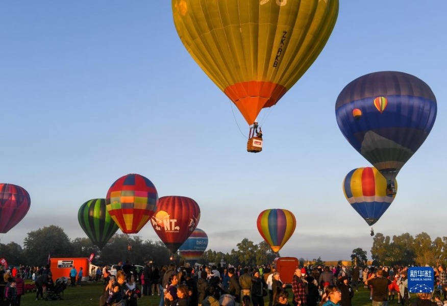 3月15日清晨，在新西兰汉密尔顿，人们聚集在湖边观看热气球升空。新华社记者 郭磊 摄