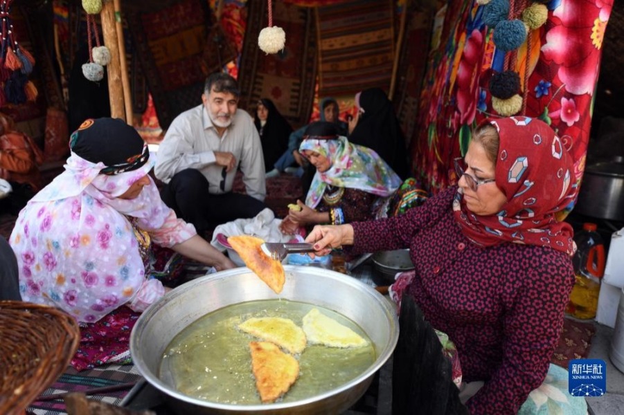 10月5日，在伊朗首都德黑兰，人们身着传统服饰制作特色美食。新华社记者 沙达提 摄