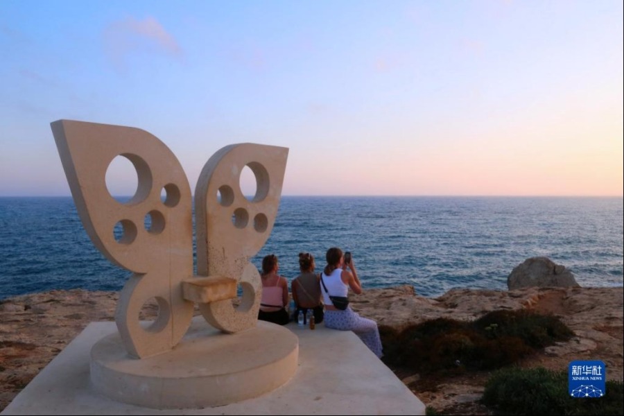 6月26日，人们在塞浦路斯圣纳帕“爱之桥”拍摄海边落日。新华社记者 郭明芳 摄