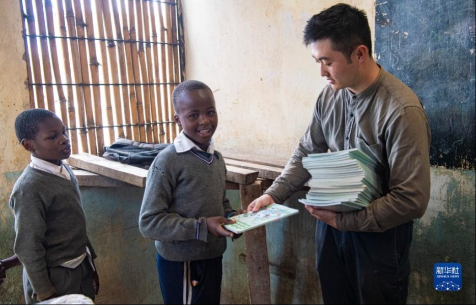 4月19日，在肯尼亚内罗毕马萨雷贫民区的一所小学，刘宜孟翰为学生们发放书本。新华社记者 李亚辉 摄