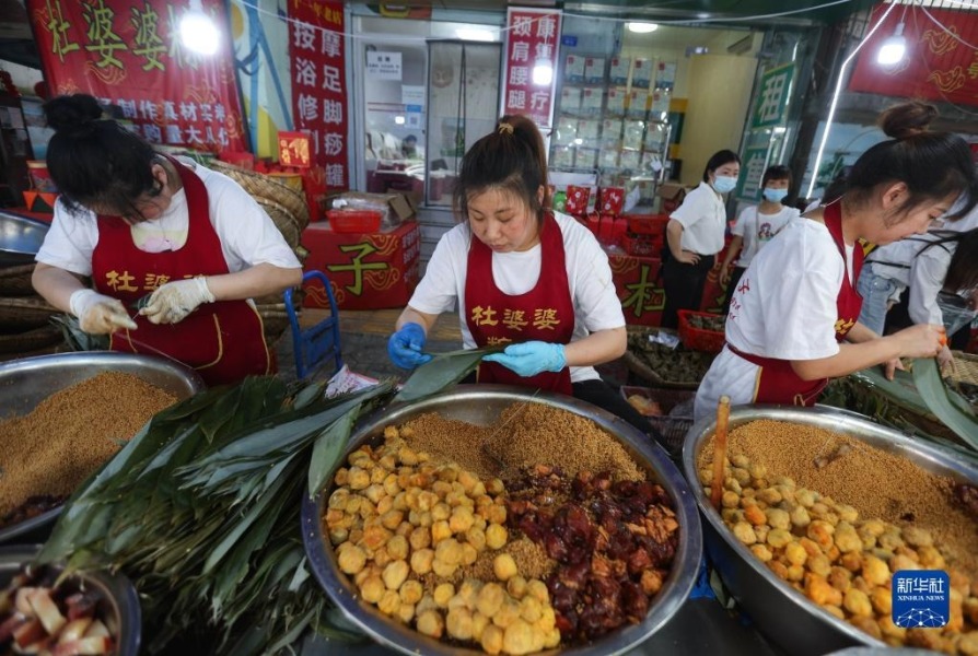 5月30日，在成都市驷马桥街道马鞍东路，粽子店铺的工作人员在现场制作粽子。新华社记者 江宏景 摄