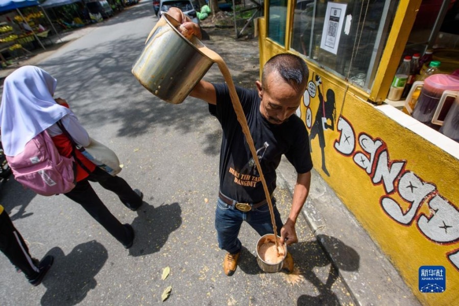 5月18日，在马来西亚雪兰莪州的必打灵查亚，穆赫德·扎布里在制作拉茶。穆赫德·扎布里在必打灵查亚经营拉茶店已超过20年，他制作的拉茶深受当地居民喜爱。新华社发（张纹综摄）