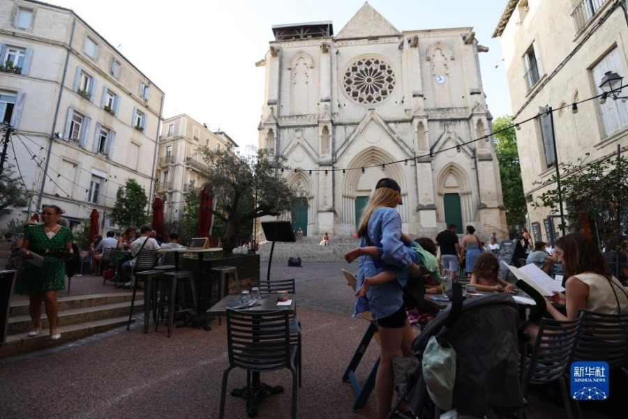 7月17日，人们在法国蒙彼利埃的圣罗克教堂前用餐。新华社记者高静摄