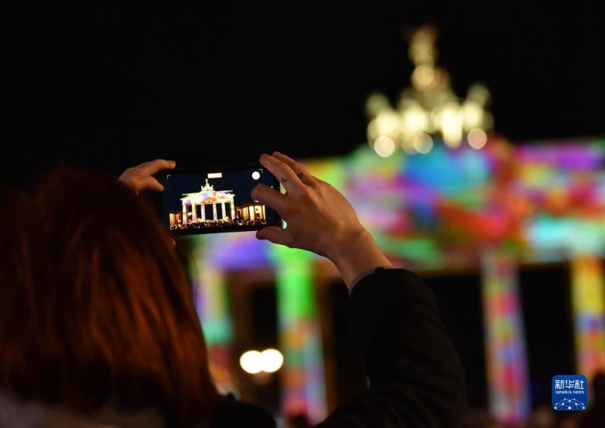 10月6日，在德国柏林，一名游客拍摄被灯光点亮的勃兰登堡门。新华社记者 任鹏飞 摄