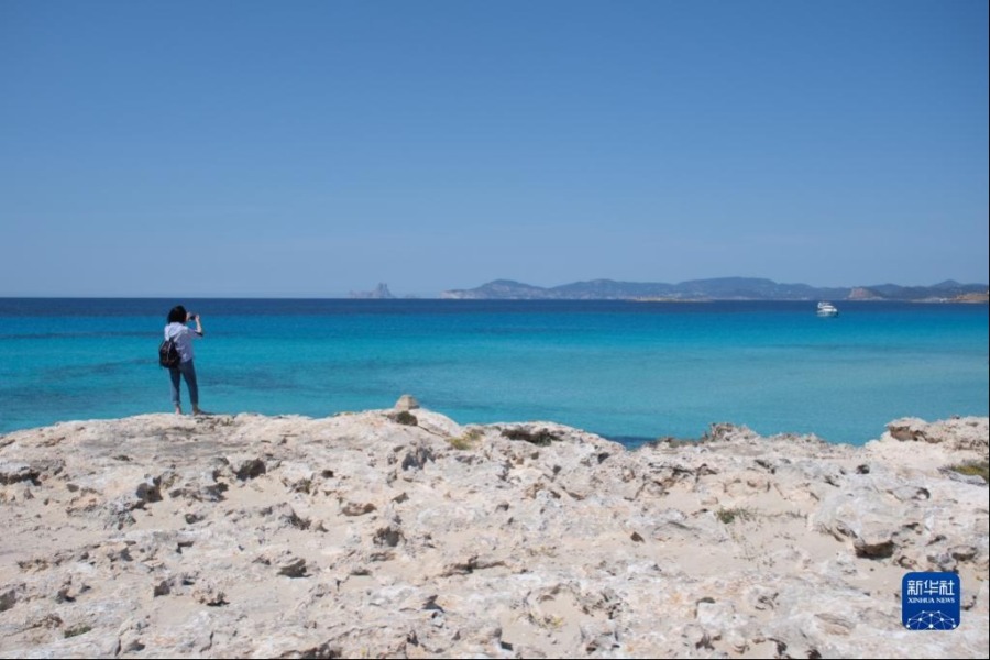 4月11日，一名游客在西班牙巴利阿里群岛福门特拉岛海边游览。新华社记者 孟鼎博 摄