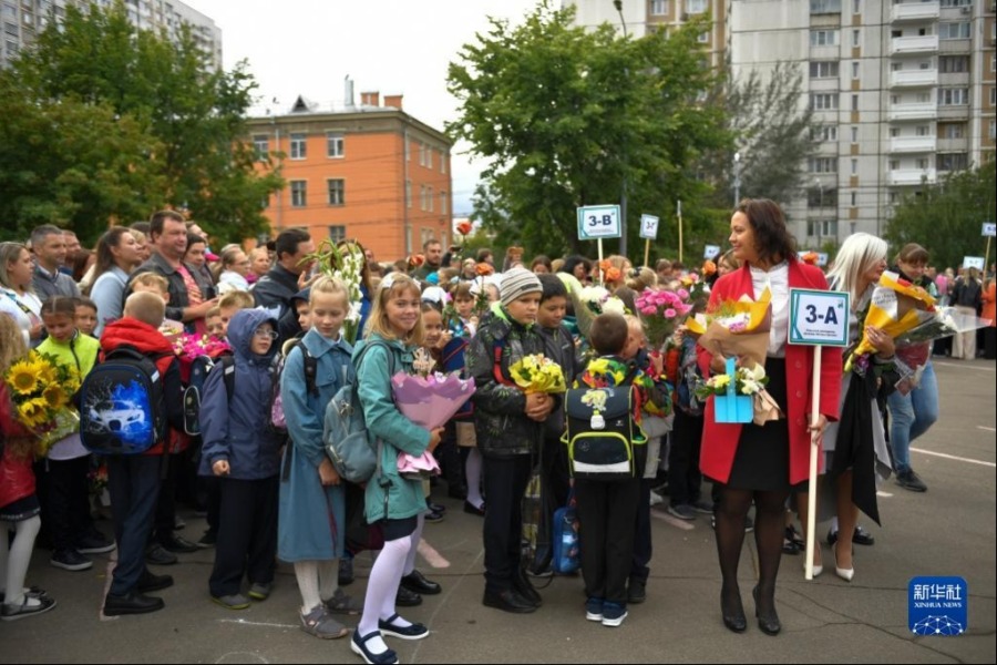 9月1日，在俄罗斯首都莫斯科，学生们捧着花束参加开学典礼。新华社发（亚历山大摄）